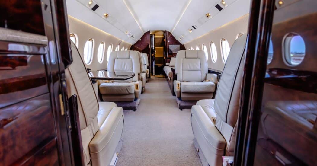 Interior of a luxurious private jet with leather seats, wooden accents, and ambient lighting.