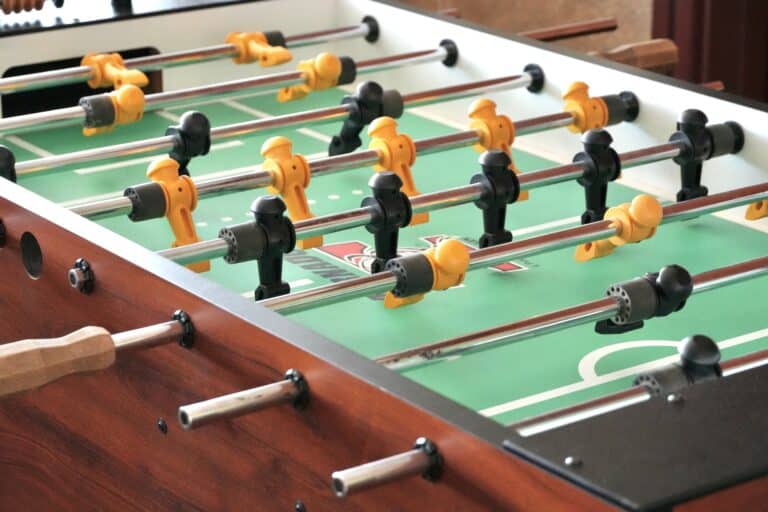 Close-up of a foosball table with black and yellow player figures on metal rods.